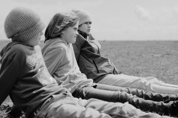 Three children sitting on a meadow. Still from the film »Planetary Boundaries of Freedom« | © Sebastian Wunderlich / PIK